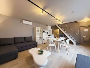 Ein stilvoller Wohnbereich mit Sofa, Esstisch, Stühlen und einer Treppe.
