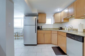 A modern kitchen with a built-in refrigerator, wooden cabinets, a granite countertop, and a dishwasher.