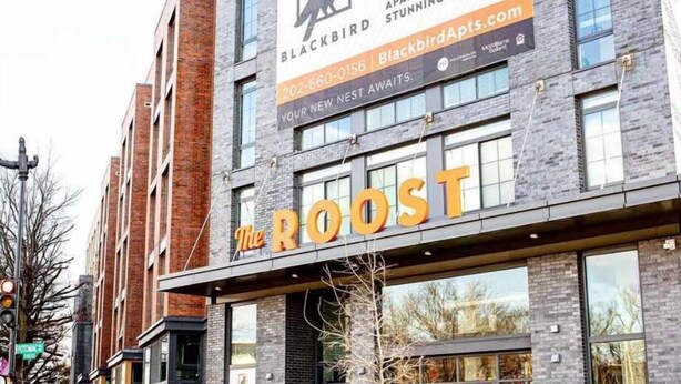 Een gebouw met een bordje voor 'The Roost' en een advertentie van Blackbird Apartments.