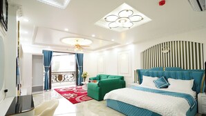 A modern hotel room with a large bed, a green sofa, a desk, and a balcony with curtains. - Legacy Hotel Ninh Binh (Hoa Lu)
