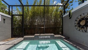 A swimming pool with a glass enclosure, surrounded by bamboo, and a decorative sun mural on the wall. - No carpet 4BD Home: with Pool and Grill Near Magic (Kissimmee)