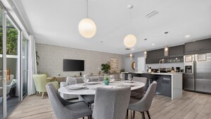 A modern kitchen with a central island, built-in appliances, and a dining area with a round table and chairs. - No carpet 4BD Home: with Pool and Grill Near Magic (Kissimmee)