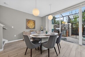A dining area with a round table, grey chairs, and pendant lighting.