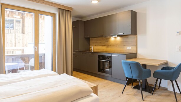A modern hotel room with a bed, a small kitchenette, and a dining area with two chairs. - Studio für 2 Personen by Interhome (Mittersill)