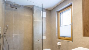 A modern bathroom with a glass-enclosed shower, a toilet, and a sink. - Studio für 2 Personen by Interhome (Mittersill)