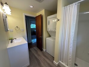 Bathroom features a washing machine, shower area, and a sink.