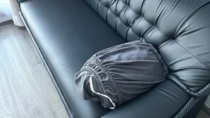 Un canapé en cuir noir avec un coussin à motif matelassé.