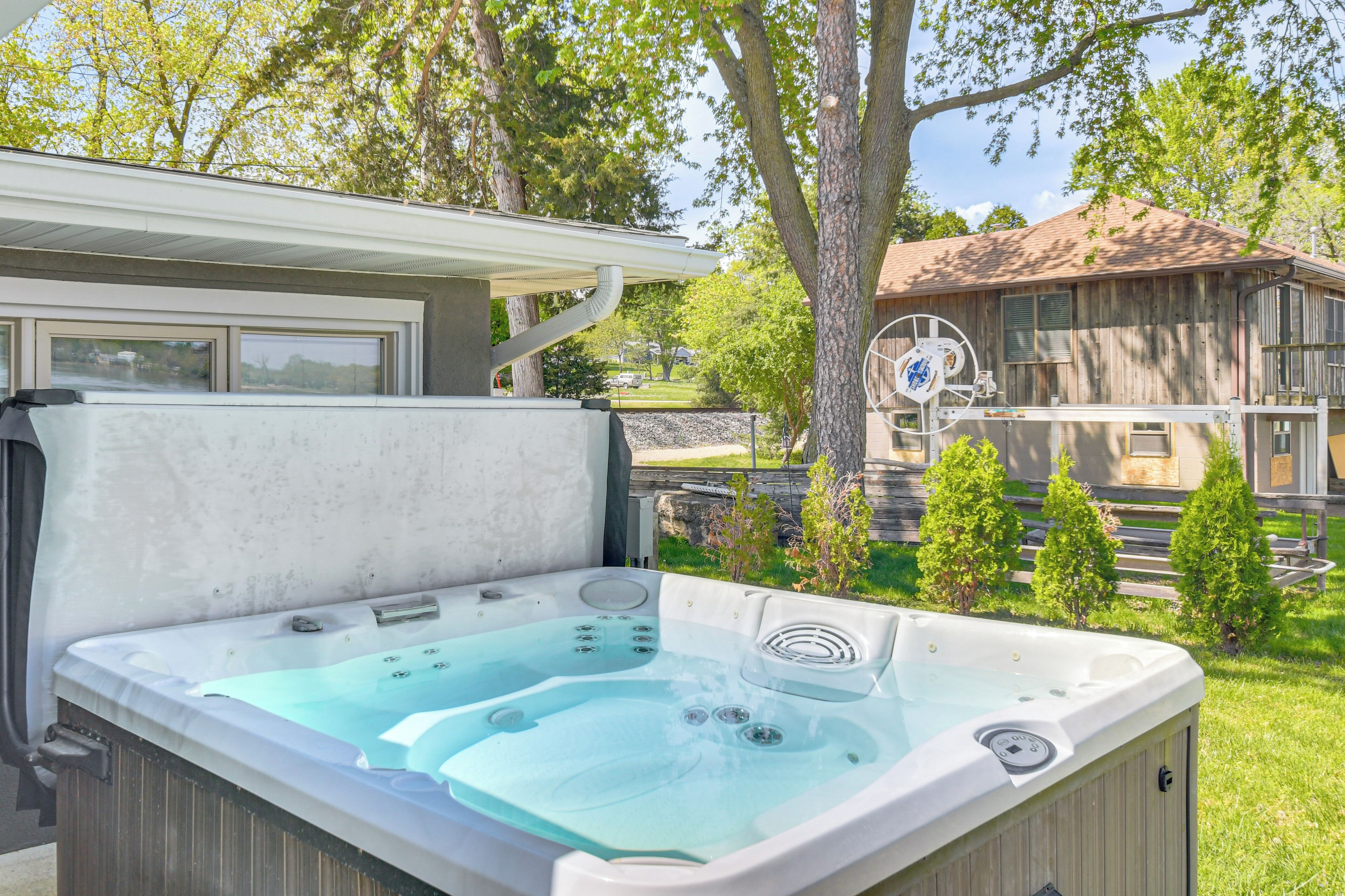 Un bain à remous dans un jardin, avec une maison en bois en arrière-plan.