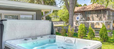 Un bain à remous dans un jardin, avec une maison en bois en arrière-plan.