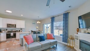 Ein modernes Wohnzimmer mit einem grauen Sofa, einem gemusterten Teppich und einem Kamin.