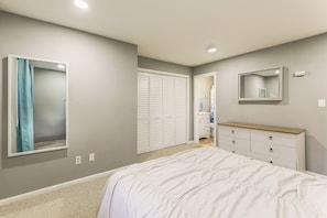 Um quarto com cama, penteadeira, guarda-roupa e espelho.