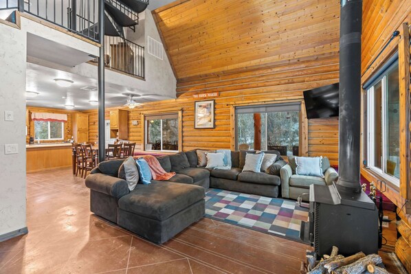 Un vaste espace de vie comprenant un grand canapé d’angle, une cheminée et un coin repas avec des meubles en bois.