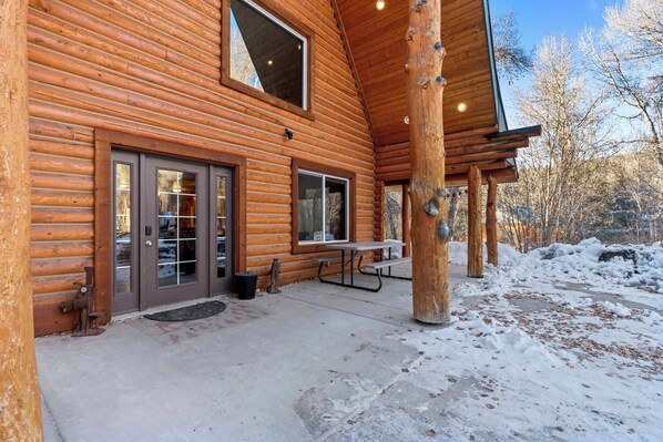 A log cabin with a covered patio, large windows, and a bench. - Evy's Cabin, 2 Miles to National Forest Land – Snowmobiling and Side-by-Siding (Heber City)