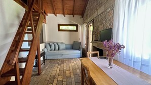 Un salon chaleureux avec un escalier en bois, un canapé, une table en bois et une cheminée.