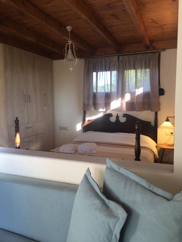 Una camera da letto con soffitto in legno, un letto con testiera, un comodino con una lampada e un armadio.