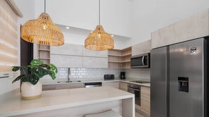 Una cocina moderna con un refrigerador de acero inoxidable, un microondas, un tostador y una isla grande con taburetes de bar.