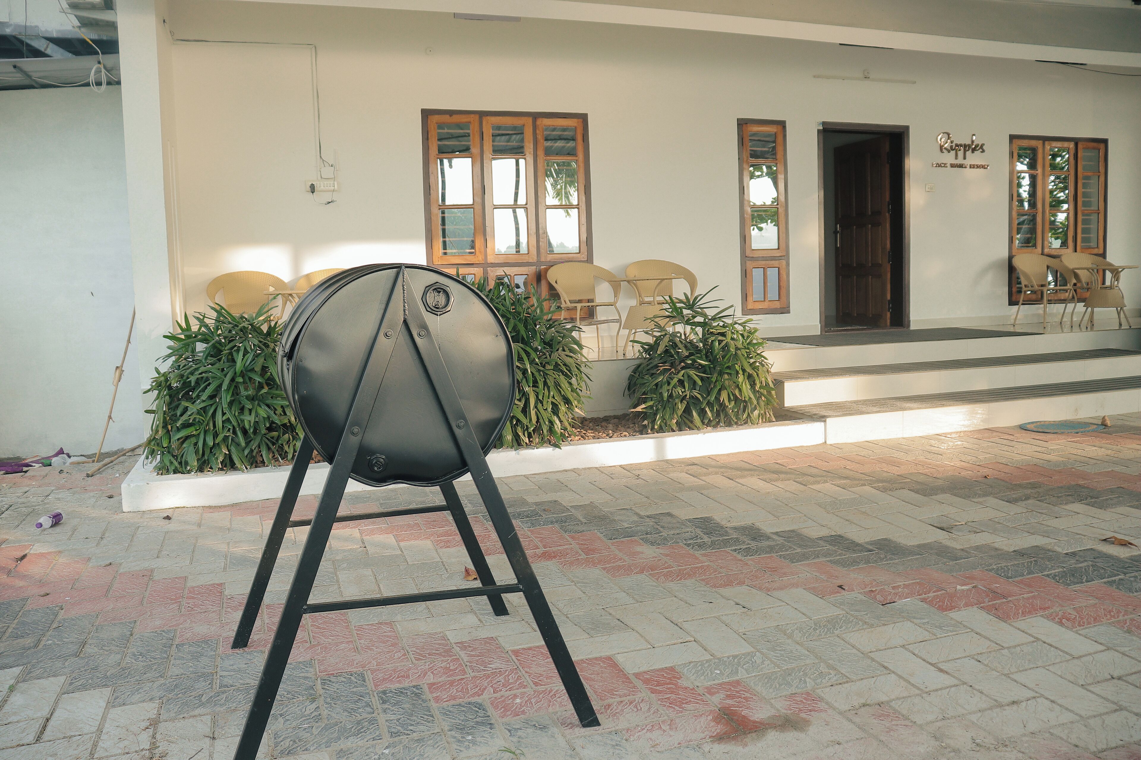 A building with a tiled entrance area, a grill outside, and several chairs near the entrance.