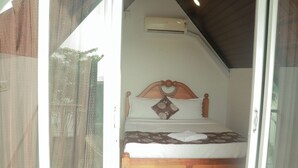 A bedroom with a wooden bed, a patterned pillow, and an air conditioning unit on the wall.