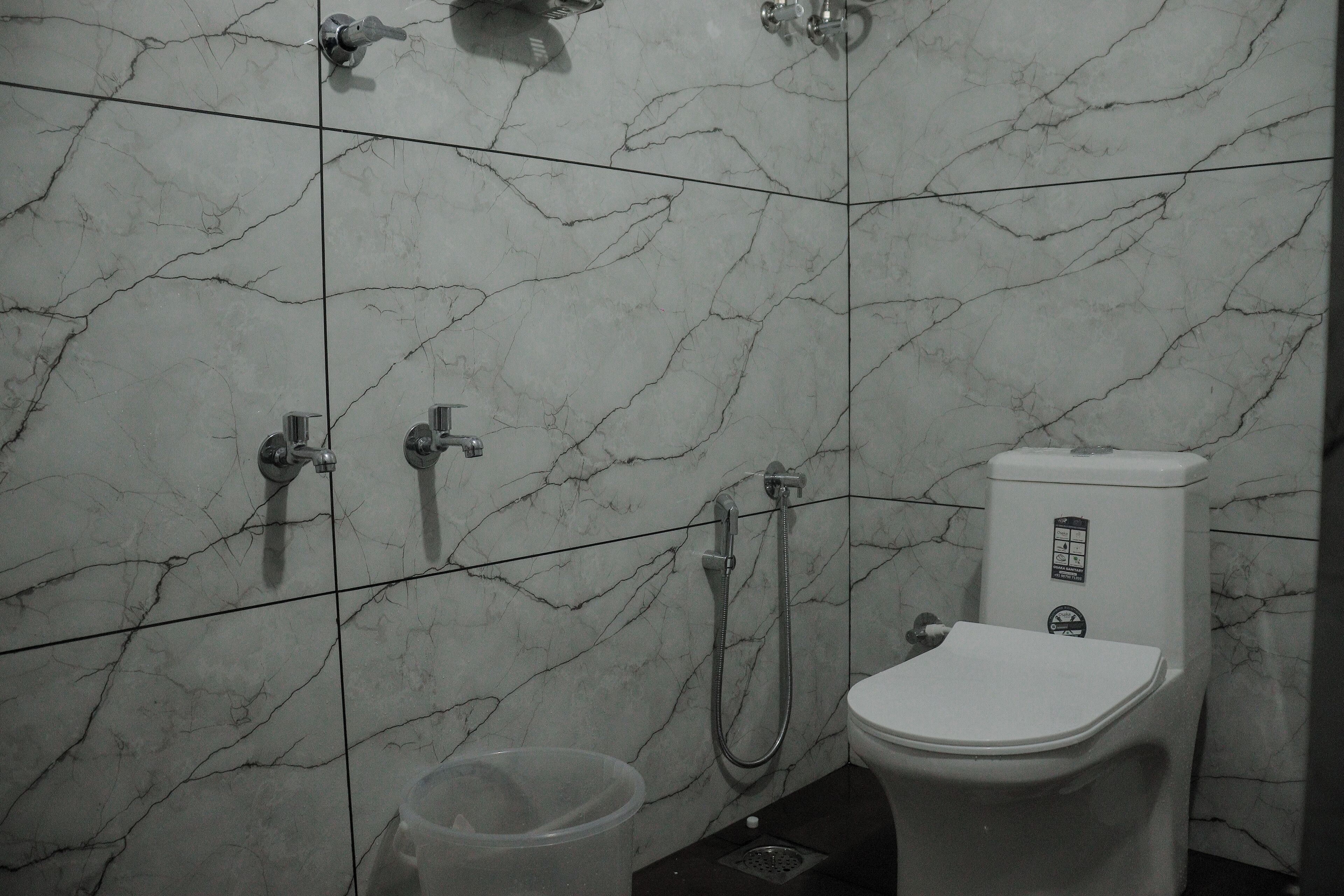 Un baño con inodoro, ducha y cubo de basura.