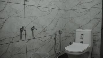 Un baño con inodoro, ducha y cubo de basura.