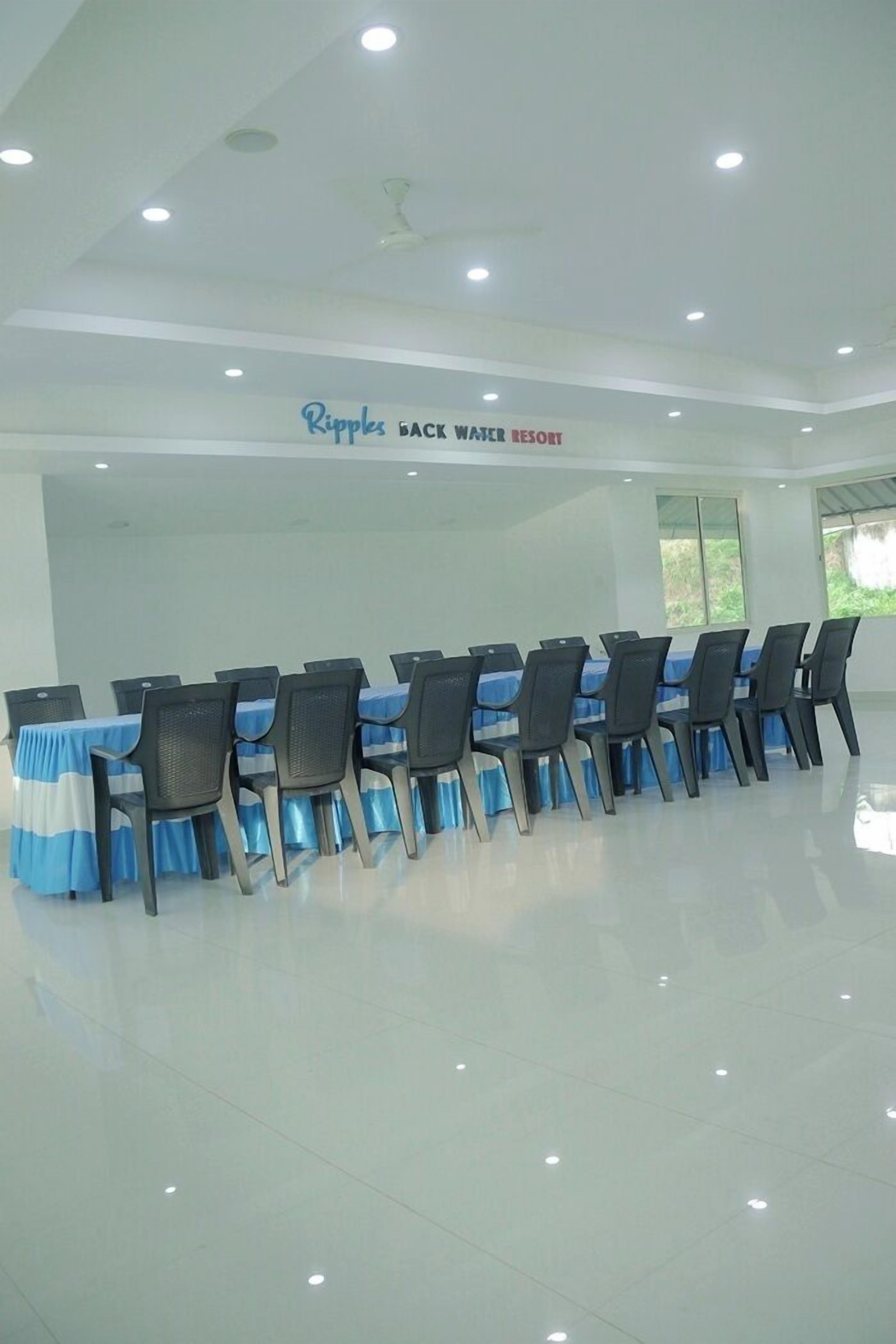 A conference room at Ripples Backwater Resort with a long table and chairs, large windows, and a ceiling fan.