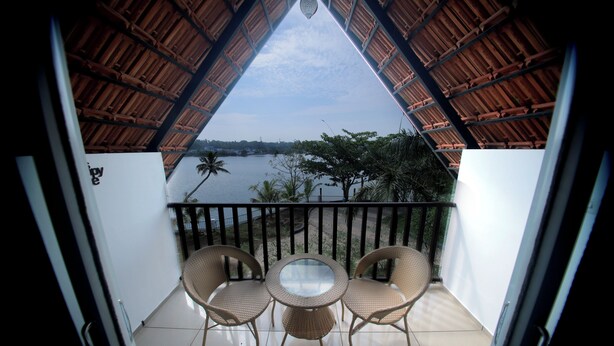 A balcony with a thatched roof, a round table, and two wicker chairs.