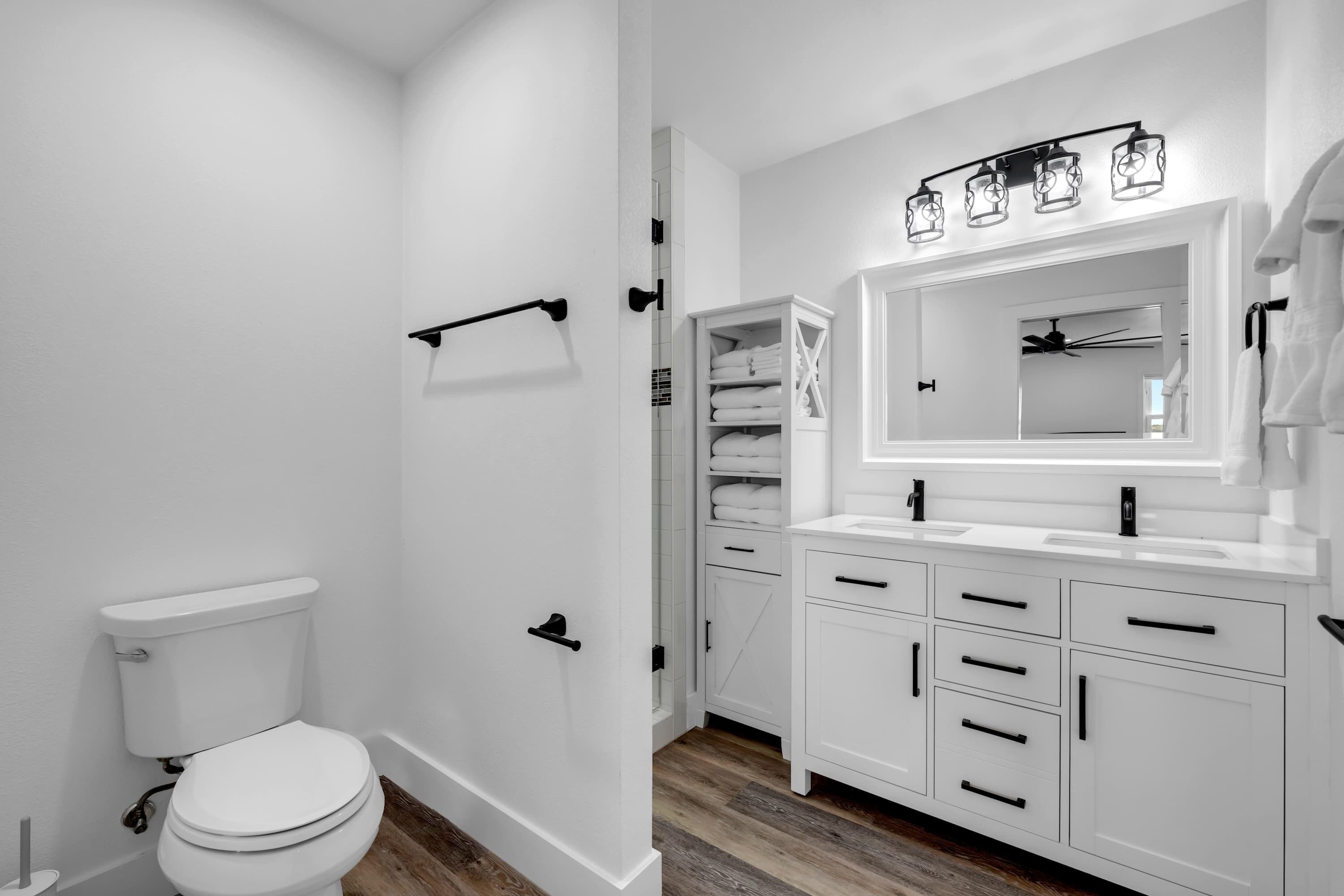 Ein modernes Badezimmer mit Toilette, Waschtisch mit Spiegel und Handtuchhalter.