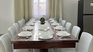 A conference room with a long table set for a meeting, white chairs, a small plant, and a refrigerator. - Ivory Bloom - Spacious 4-BR w/ WiFi, AC, Large Space in Puerto Princesa, Palawan (Puerto Princesa)