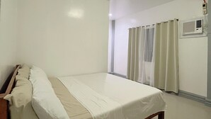 A bedroom with a bed, a window with curtains, an air conditioning unit, and a ceiling light. - Ivory Bloom - Spacious 4-BR w/ WiFi, AC, Large Space in Puerto Princesa, Palawan (Puerto Princesa)