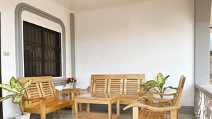 A room with a wooden sofa set, a small table, and two potted plants. - Ivory Bloom - Spacious 4-BR w/ WiFi, AC, Large Space in Puerto Princesa, Palawan (Puerto Princesa)