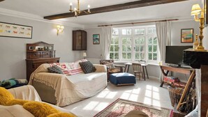 A cozy room with a bed, a desk, a television, and a window with curtains. - Homely Cottage & Garden nr Praa Sands & Marazion (Rosudgeon)