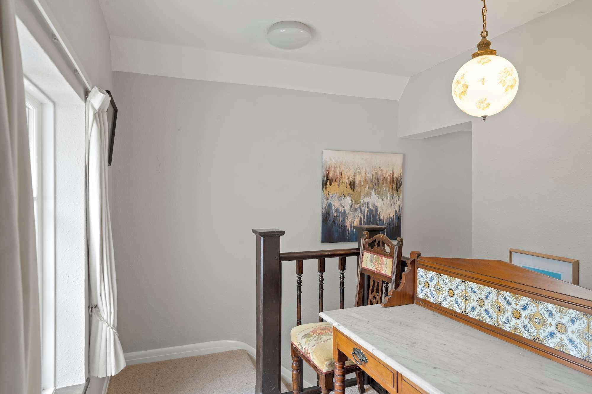 Ein Essbereich mit Holztisch und Stühlen, einer Pendelleuchte und einem Gemälde an der Wand.