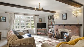 A cozy living room with a fireplace, a television, and a bookshelf. - Homely Cottage & Garden nr Praa Sands & Marazion (Rosudgeon)