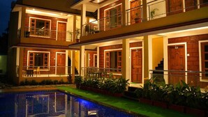 Un edificio de varios pisos con piscina, balcones y puertas de madera.