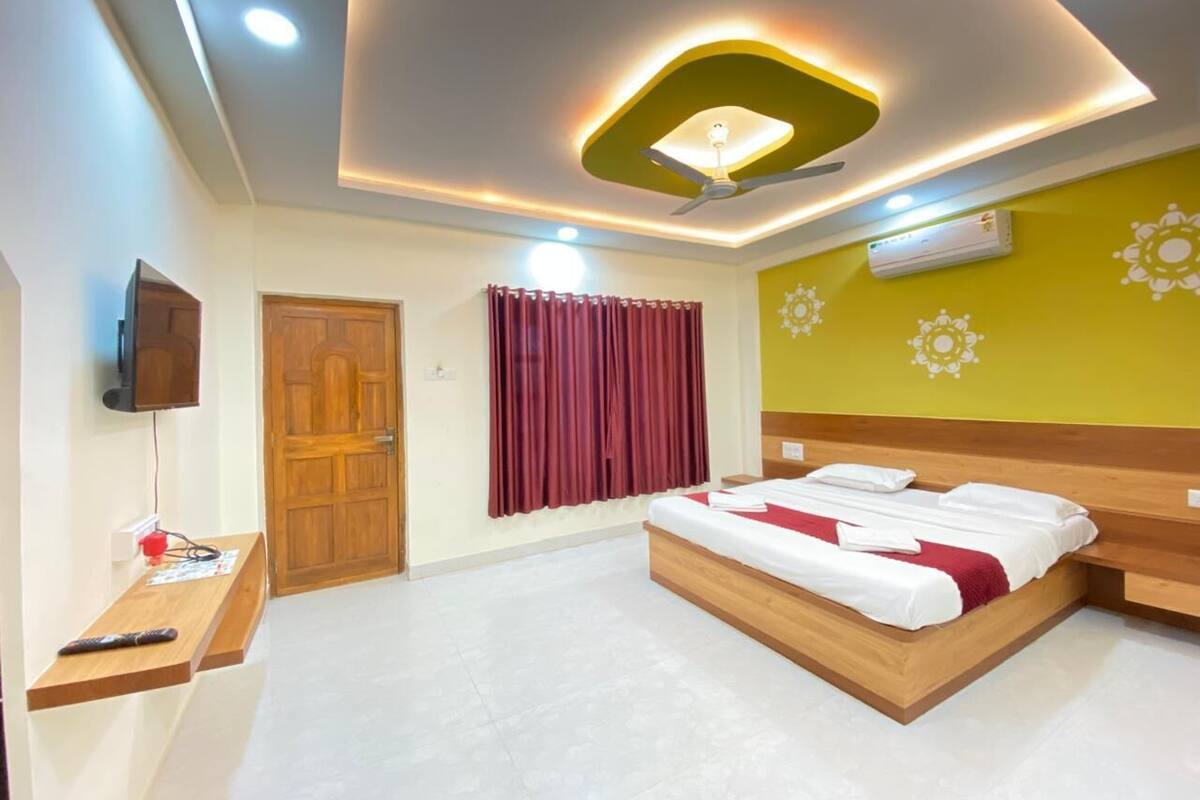 Ein Hotelzimmer mit einem Bett, einem Fernseher, einem Deckenventilator und einer Wand-Klimaanlage.