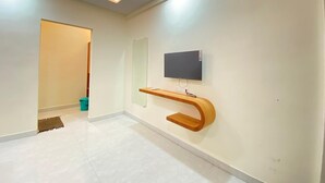 Una habitación moderna y bien iluminada, con un televisor de pantalla plana montado en la pared, una mesita consola de madera y piso de baldosas.