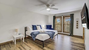 A bedroom with a bed, a nightstand, a ceiling fan, and a window with curtains.