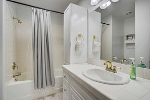 Ein Badezimmer mit Badewanne, Dusche, Waschbecken und Spiegel.