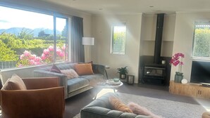Ein modernes Wohnzimmer mit einer Couch, Sesseln, einem Couchtisch und einem Kamin.