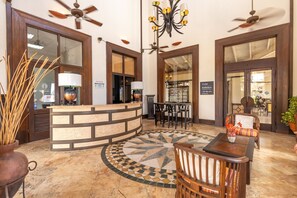 A reception area with a curved counter, a chandelier, ceiling fans, and a tiled floor with a geometric pattern.