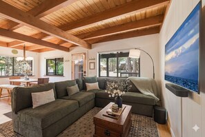 Una sala de estar con un sofá modular, una mesa de centro y un televisor montado en la pared.