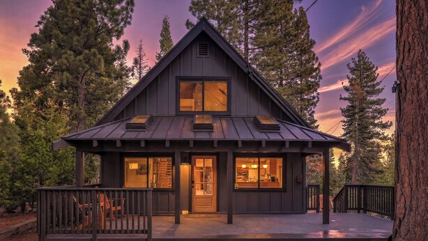 A cabin with a front porch, large windows, and a deck.