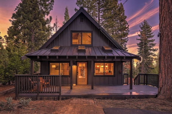 A cabin with a front porch, large windows, and a deck.