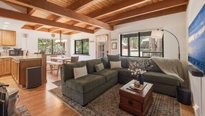 A spacious living area with a wooden ceiling, a sectional sofa, a coffee table, and a large window.