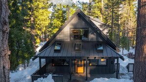 A cabin with a gabled roof, a front porch, and a chimney.