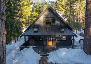 A cabin with a gabled roof, a front porch, and a chimney.