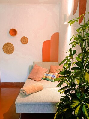 A cozy room with a sofa, pillows, a wall-mounted light, and a plant. - Villa do Sol (Cascais)