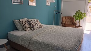 Ein Schlafzimmer mit Bett, Stuhl, Pendelleuchte, Pflanze und einer Wand mit einem Schild.