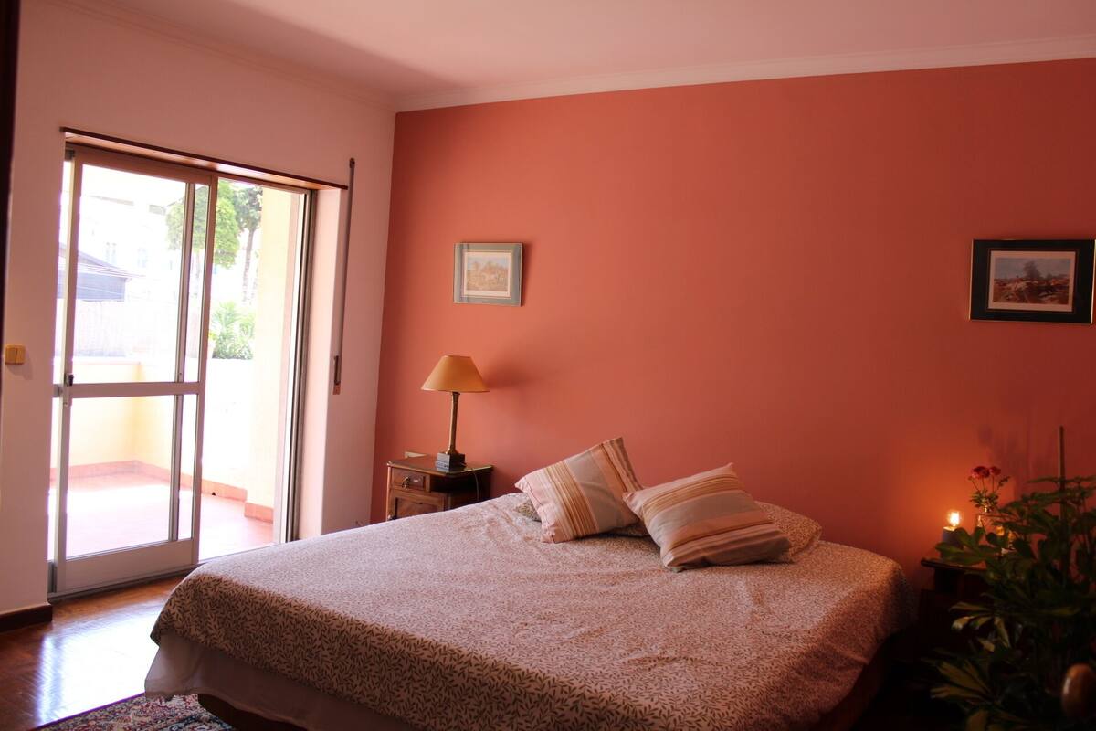Ein Schlafzimmer mit einem Bett, einem Nachttisch, einer Lampe und zwei gerahmten Bildern an der Wand.