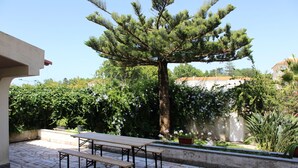 Eine Terrasse im Freien mit Steinboden, einem Holztisch und Bänken.